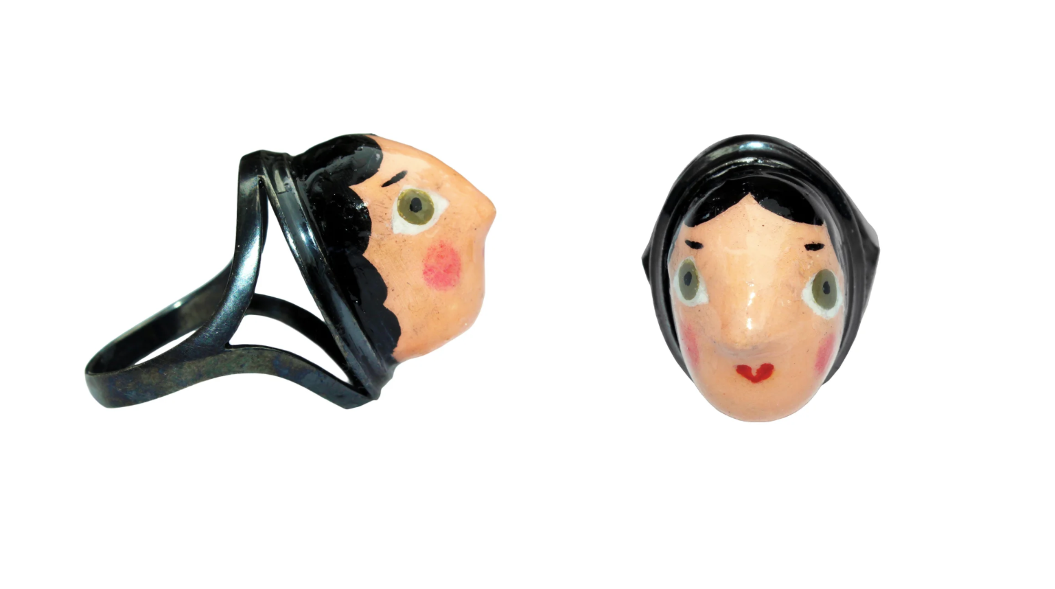Two sculptural rings featuring hand-painted ceramic faces with black hair and expressive facial details.